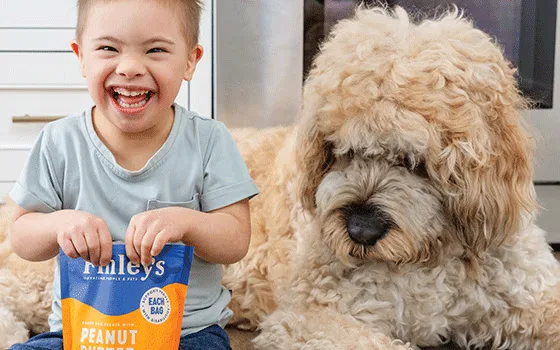 A child holding a bag of Finley's next to a dog