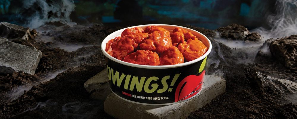 A black Halloween-themed Applebee's bucket filled with sauced boneless wings