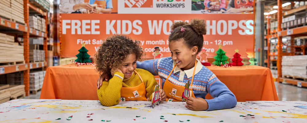 Children in Home Depot aprons building the holiday car ornament at a Kids Workshop.