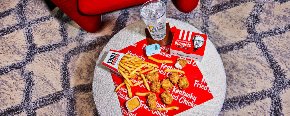KFC nuggets, fries and dipping sauces on a red KFC wrap on an ottoman