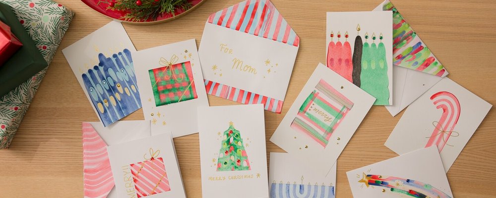 Handmade paint-scraped holiday cards and envelopes on a table
