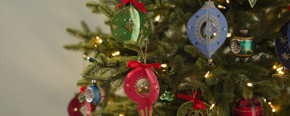 Dimensional paper ornaments in red, green and blue hanging on a Christmas tree