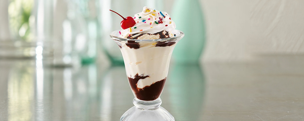 Vanilla ice cream sundae with chocolate sauce, whipped cream, sprinkles and a cherry