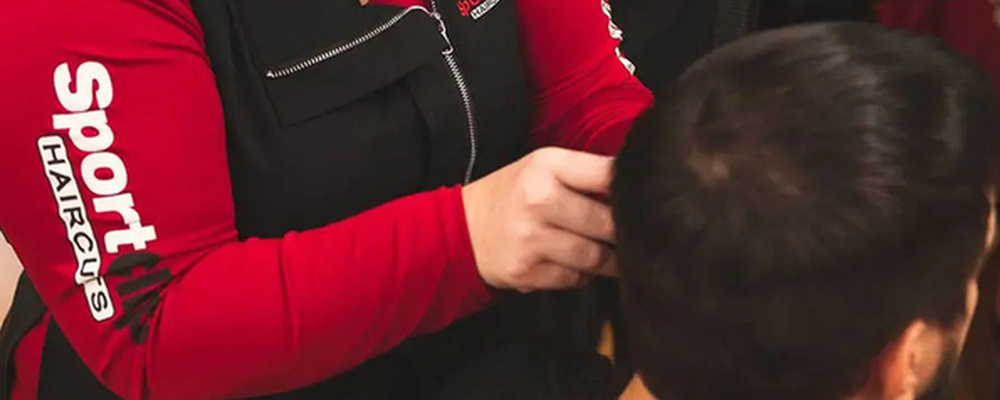 A Sport Clips stylist cutting a customer's hair, seen from behind